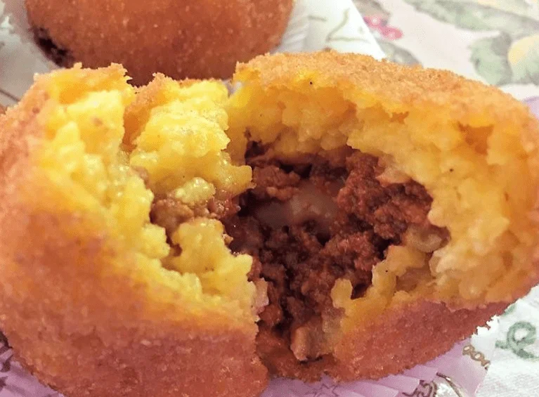 Meat arancini, golden and crispy, served on a Sicilian ceramic plate