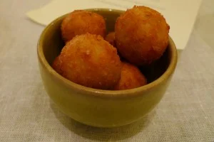 Arancine di riso in bianco dorate con cuore di besciamella e formaggio su piatto bianco