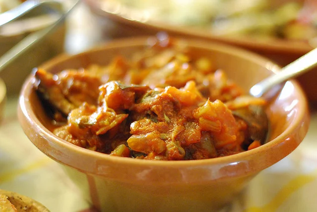 Caponata di finocchi con olive e pinoli servita fredda in piatto di ceramica siciliana