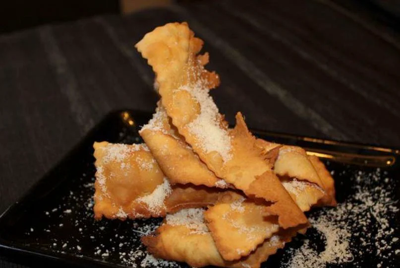Golden Sicilian Carnival fritters dusted with icing sugar