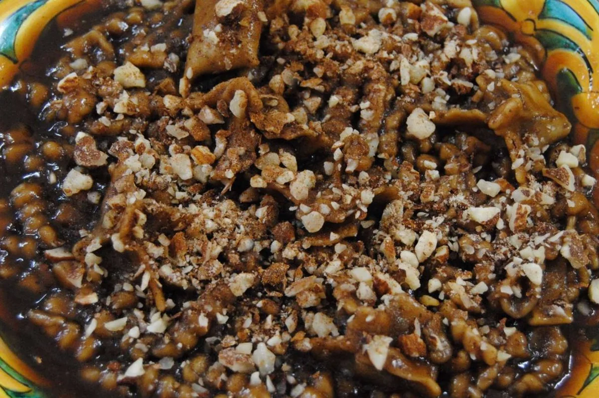 Cuḍḍureḍḍi con il mosto serviti con mandorle tostate su piatto tradizionale siciliano