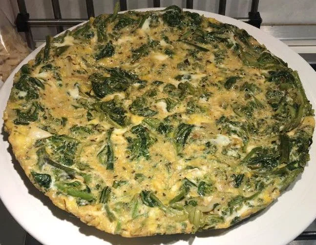 Frittata di mazzareddi su piatto rustico con verdure selvatiche siciliane