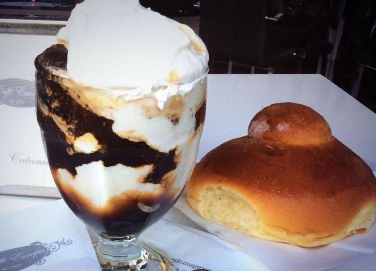 Granita di caffè con panna servita in bicchiere con brioche siciliana