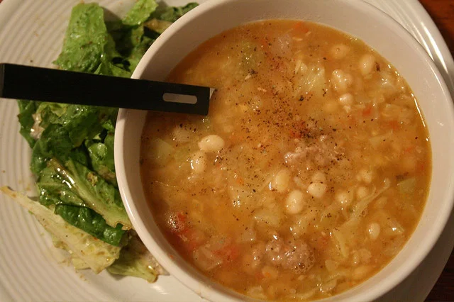 Minestra di cavolo e fagioli siciliana servita con pane tostato e pecorino in ciotola rustica