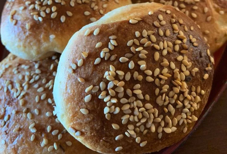 Panini di cena messinesi dorati e ricoperti di sesamo su vassoio tradizionale siciliano