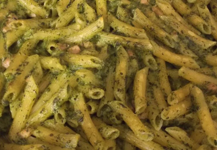 Pasta col pesto di spinaci, ricotta e pancetta servita in piatto in maiolica siciliana