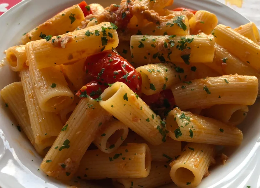 Pasta con tonno e pomodorini Pachino servita in piatto di ceramica siciliana con prezzemolo fresco