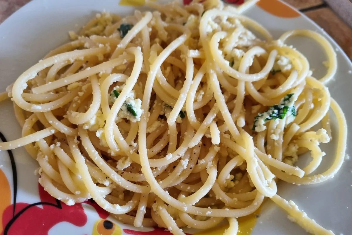 Pasta cû riquagghiu cremosa con uova e pecorino, guarnita con prezzemolo fresco