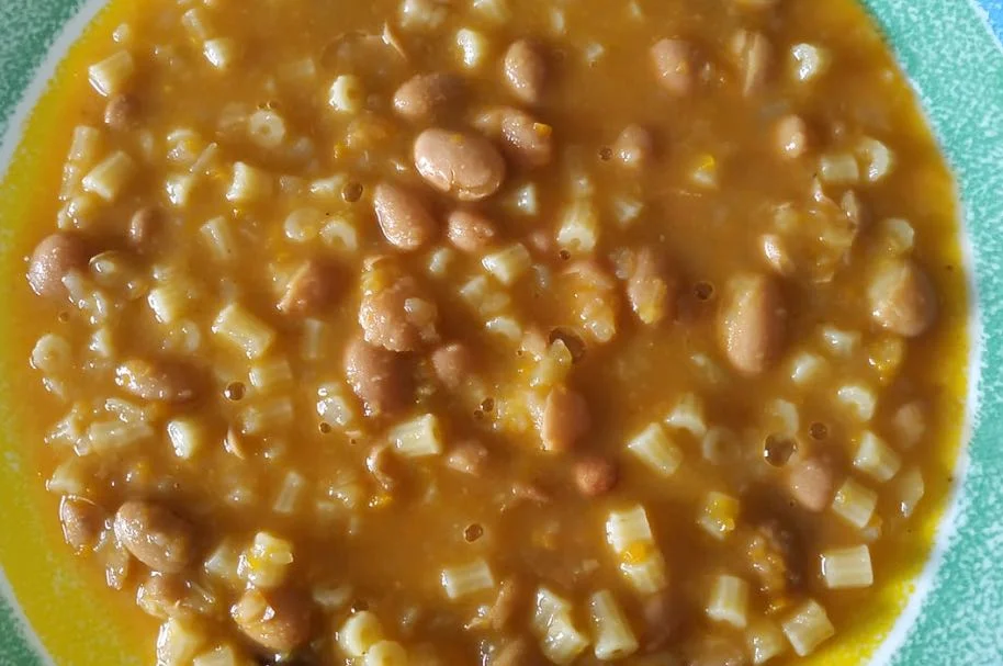 Ciotola di pasta e fagioli cremosa servita calda con prezzemolo fresco