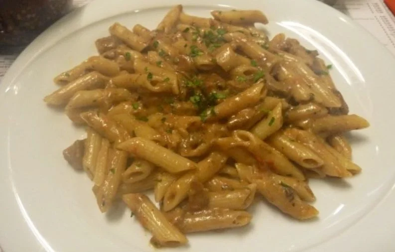 Piatto di penne alla boscaiola con funghi e salsiccia