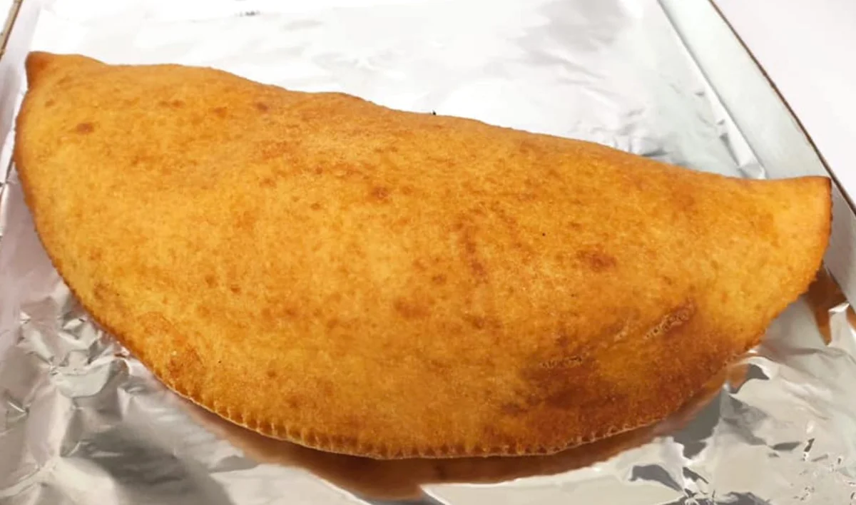 Pizza fritta di Zafferana Etnea dorata e ripiena di tuma, acciughe e olive