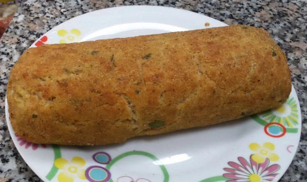 Polpettone di tonno alla siciliana dorato e tagliato a fette su un piatto con decorazione di prezzemolo e limone