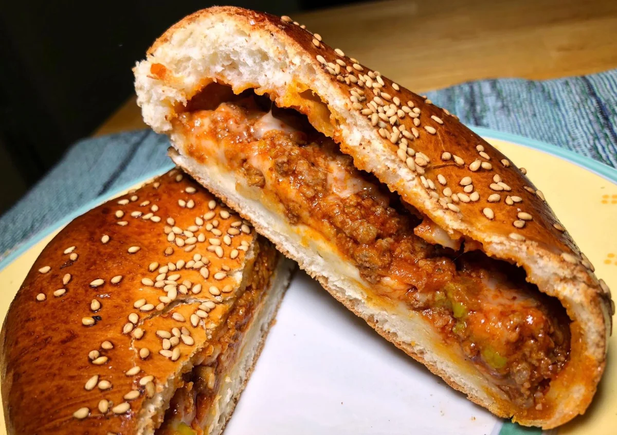 Ravazzate palermitane dorate con ripieno di ragù e piselli su un vassoio di ceramica siciliana